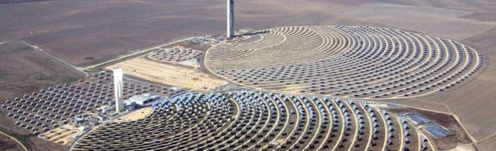 Aerial view of a concentrated solar power plant with mirrors reflecting sunlight toward a central tower